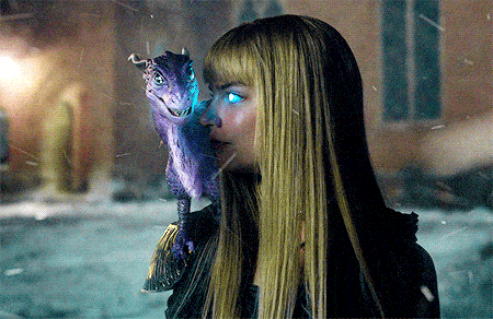 a woman with long blonde hair is holding a purple dragon with blue eyes