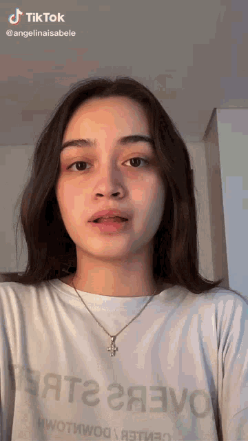 a girl wearing a necklace and a t-shirt that says tiktok on it
