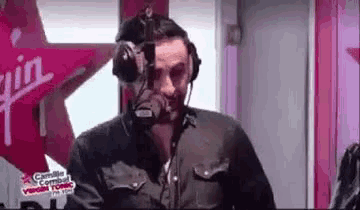 a man wearing headphones and a microphone is talking into a microphone in a radio studio .