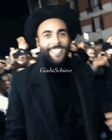 a man wearing a black hat is smiling in front of a crowd and the name giada schiavo is on the bottom right