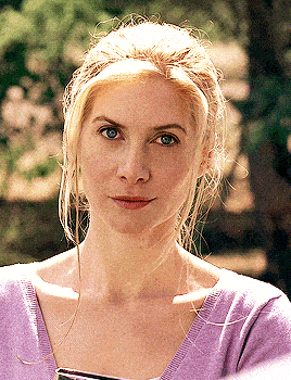a woman with blonde hair and blue eyes is wearing a purple shirt
