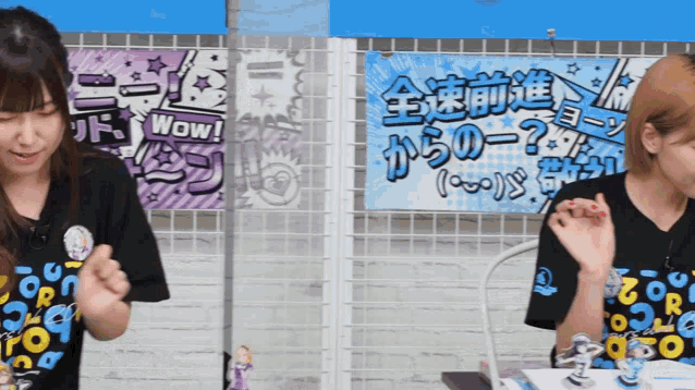 two girls are sitting in front of a sign that says wow