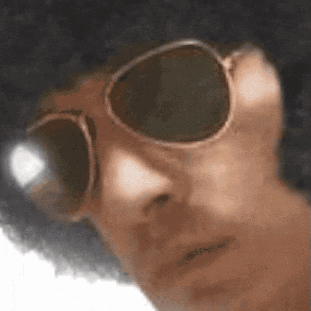 a man wearing an afro and sunglasses is looking at the camera