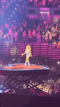 a woman is walking on a stage in front of a crowd with a sign that says block 1 on it