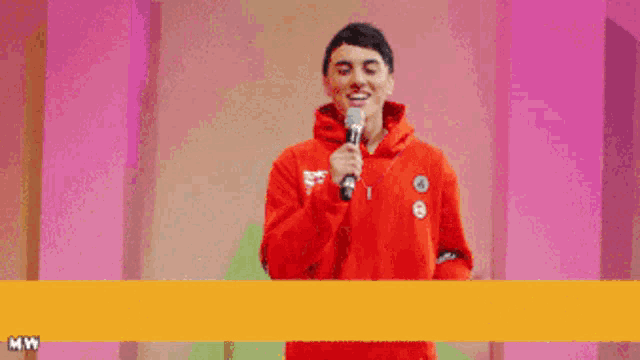 a man in a red hoodie stands in front of a banner that says made possible by