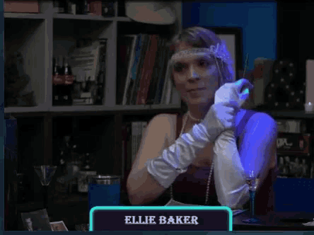 a woman wearing gloves is sitting at a table with a sign that says ellie baker on it