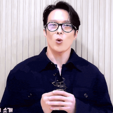 a man wearing glasses and a blue jacket is making a face