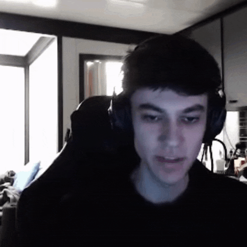a young man wearing headphones is sitting in a chair in a dark room .