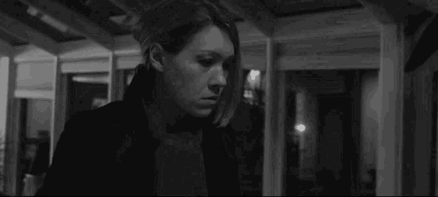 a black and white photo of a woman standing in a room .