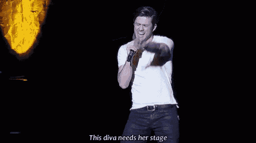 a man is singing into a microphone on stage .