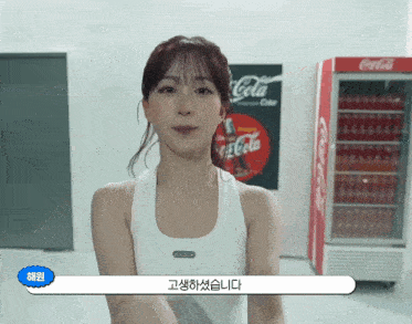 a woman is standing in front of a coca cola fridge