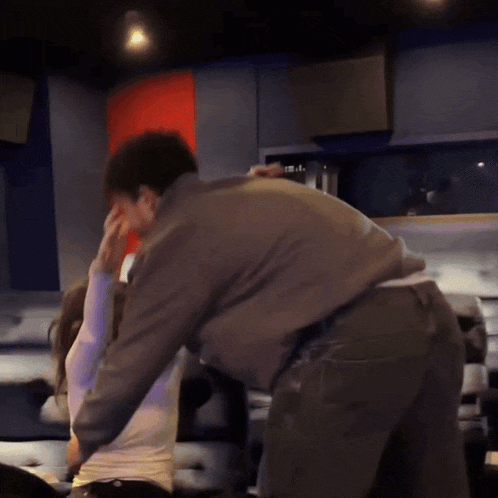 a man and a woman are dancing in a room with a red and blue wall behind them