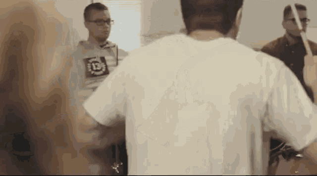 a man in a white shirt with the number 13 on it is playing drums .