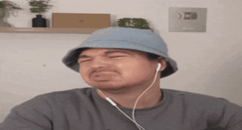 a man wearing a blue hat and ear buds is making a face
