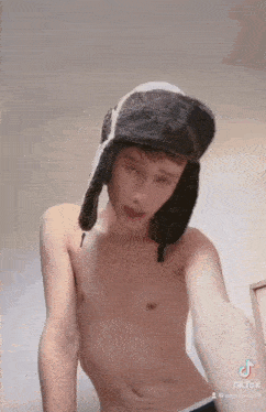 a shirtless young man wearing a fur hat .