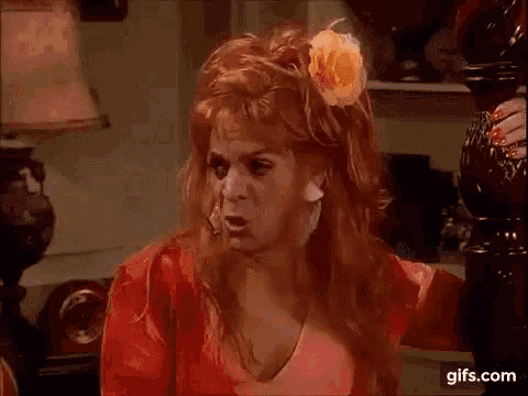 a woman with red hair and a flower in her hair is sitting in a chair .