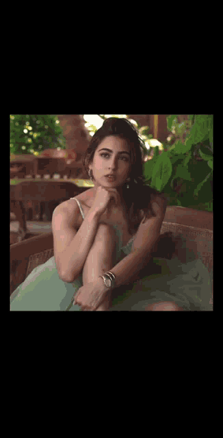 a woman in a pink and yellow dress is sitting on a couch