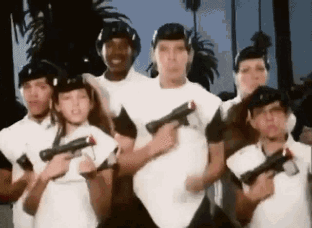 a group of people are standing next to each other holding guns in their hands .