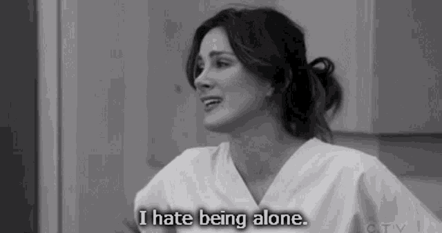 a black and white photo of a woman in scrubs saying i hate being alone .