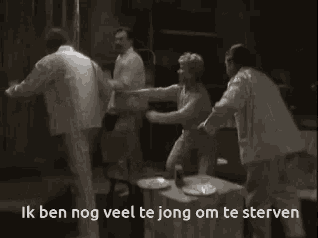 a group of people standing around a table with ik ben nog veel te jong om te sterven