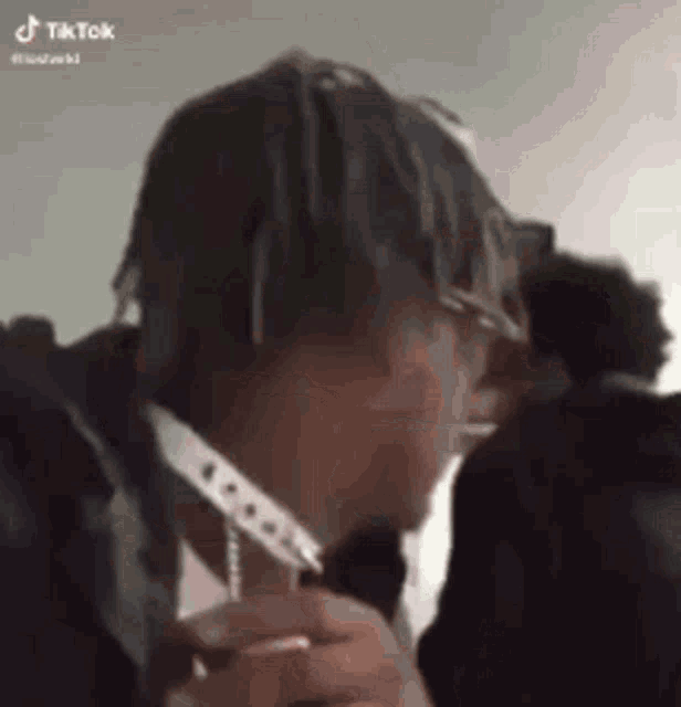 a man with dreadlocks is smoking a cigarette and holding a knife .