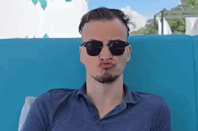 a man wearing sunglasses and a blue shirt is making a funny face .