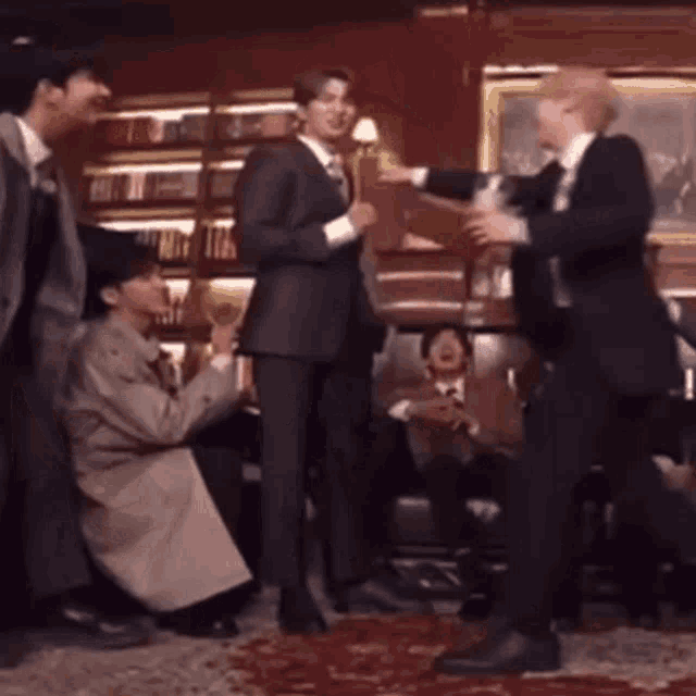 a group of men in suits are standing around a table in a room .