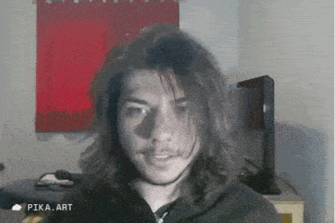 a man with long hair is standing in front of a red curtain and a pika art icon