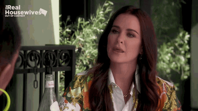 a woman is sitting at a table with a bottle of evian water in front of her .