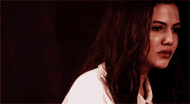 a woman with long hair is looking at the camera with a serious look on her face