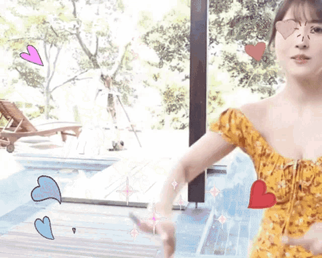 a woman in a yellow dress is standing in front of a swimming pool .