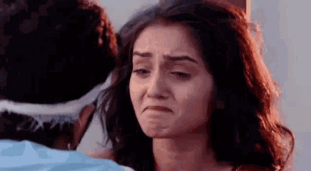 a woman is crying while looking at a man with a bandage on her head .