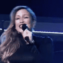 a woman is singing into a microphone in front of a blue background .