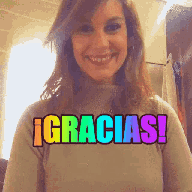 a woman is smiling in front of a rainbow colored gracias sign