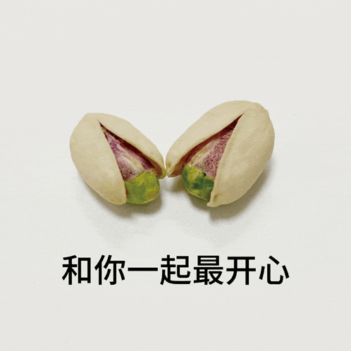 two pistachios cut in half on a white surface with chinese writing below them