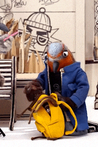 a stuffed bird in a blue coat is kneeling down with a yellow backpack