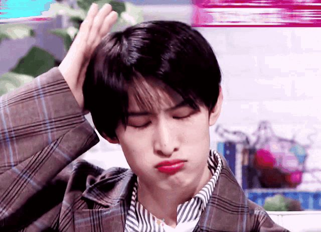 a young man wearing a plaid jacket and striped shirt is making a funny face