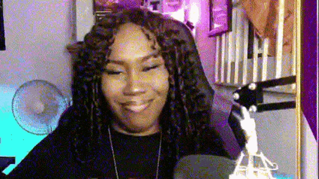 a woman is smiling in front of a microphone in a room .