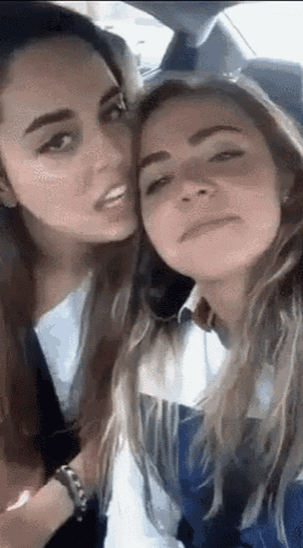 two women are making funny faces in a car .
