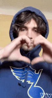 a man in a blue hoodie is making a heart with his hands