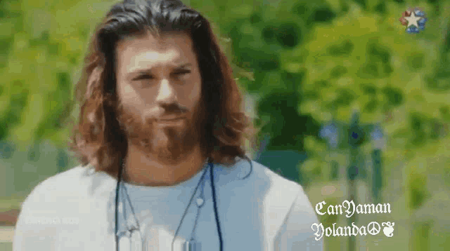 a man with long hair and a beard is wearing a blue shirt