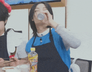 a woman in an apron drinks from a can next to a bottle of sprite
