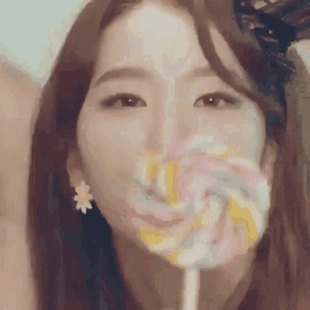 a woman is eating a colorful lollipop in front of her face .
