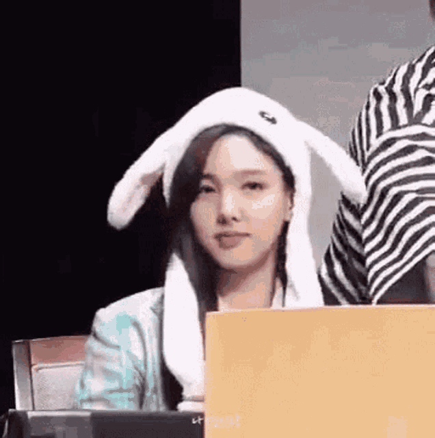 a woman wearing a bunny hat is sitting at a table with a laptop .