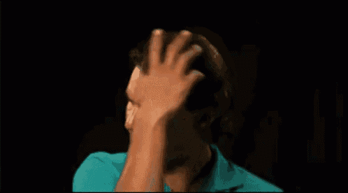 a man in a blue shirt is scratching his head against a black background