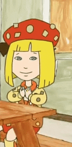 a cartoon girl with blonde hair and a red hat sits at a table