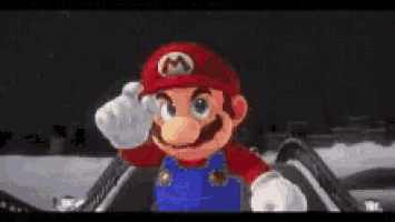 mario is wearing a red hat and overalls and giving a salute while standing in the snow .