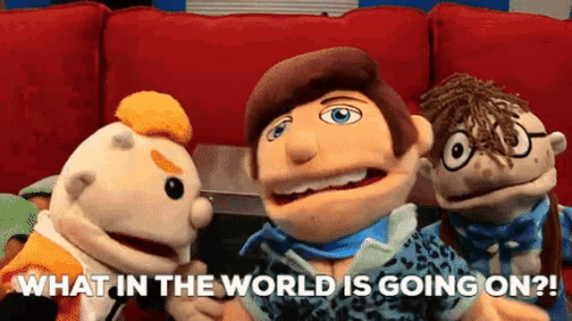 three puppets are sitting on a red couch and one of them is asking what in the world is going on ?