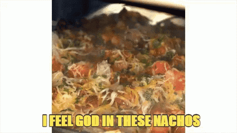 a casserole dish of nachos with the words " i feel god in these nachos " on the bottom