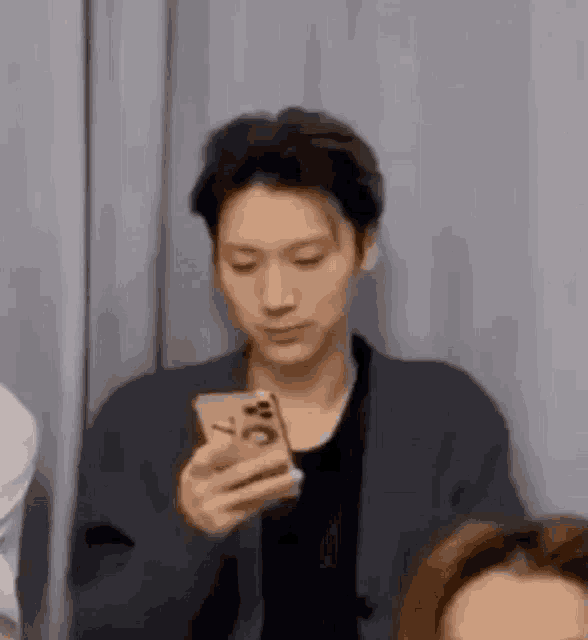 a man is holding a cell phone in his hand and making a funny face .